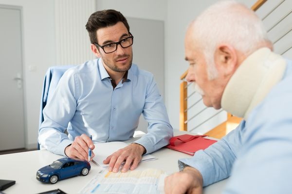 Insurance agent explaining auto insurance laws to elderly person