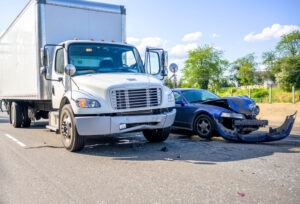 The photo depicts a collision between a car and a semi-truck. Who is liable in a truck accident in Massachusetts?